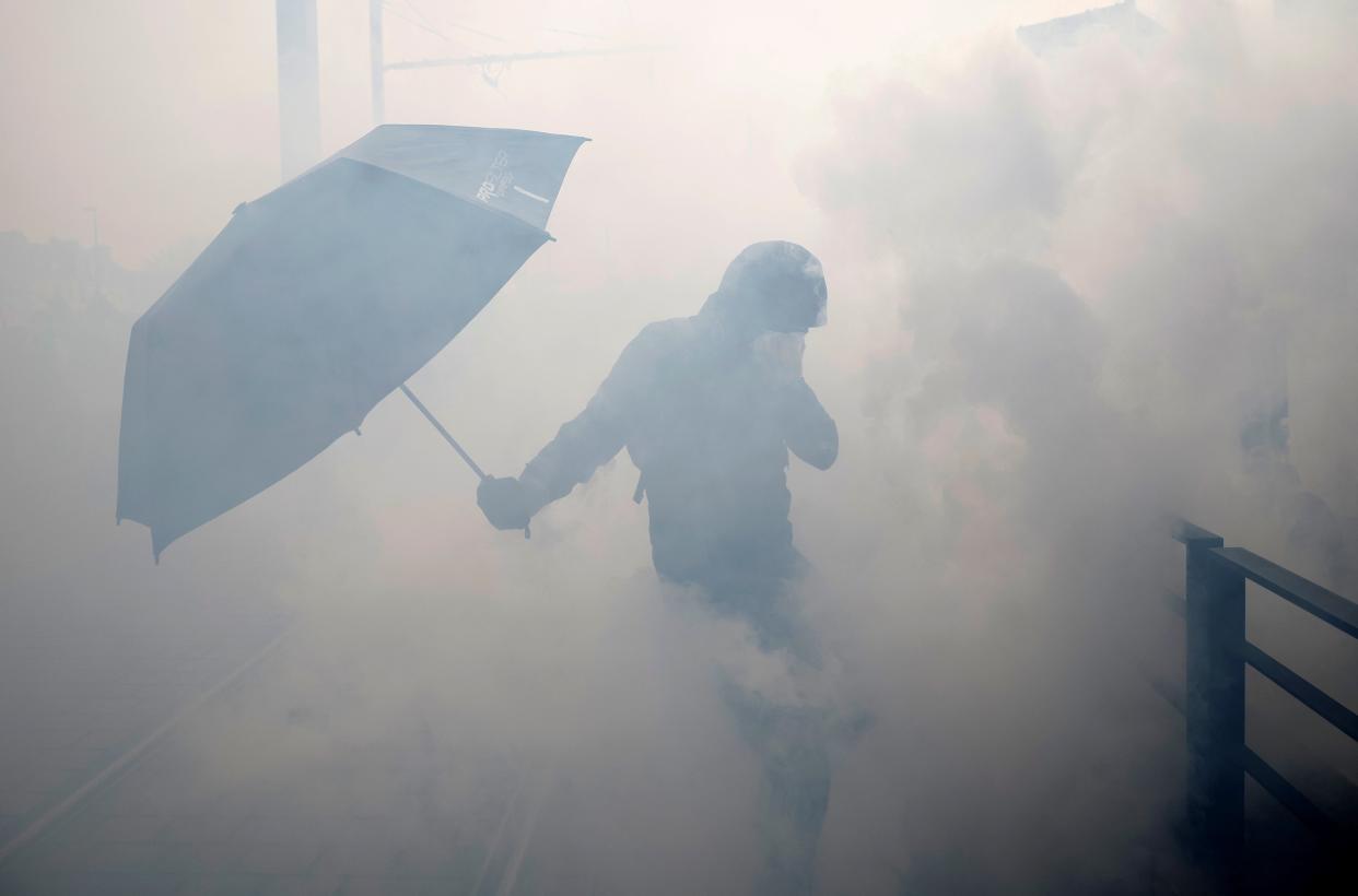 A masked protester covers their face amid tear gas in Nantes, western France (Reuters)