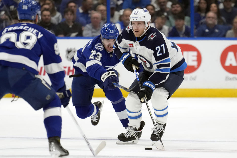 Winnipeg Jets left wing Nikolaj Ehlers (27) gets hooked by Tampa Bay Lightning center Michael Eyssimont (23) during the first period of an NHL hockey game Wednesday, Nov. 22, 2023, in Tampa, Fla. (AP Photo/Chris O'Meara)