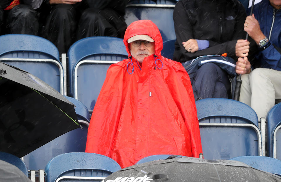 A spectator shields themselves from the rain during day one (Niall Carson/PA Wire)