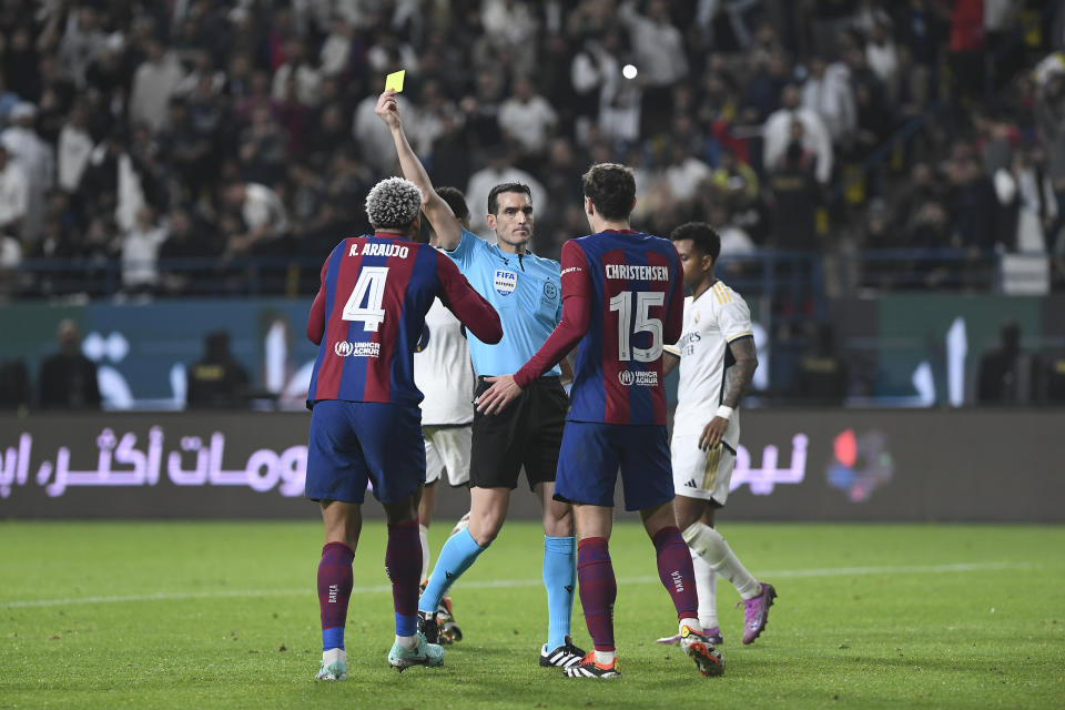 Barcelona's Ronald Araujo, left, receives a yellow card during the Spanish Super Cup final soccer match between Real Madrid and Barcelona at Al-Awwal Park Stadium in Riyadh, Saudi Arabia, Sunday, Jan. 14, 2024. (AP Photo)