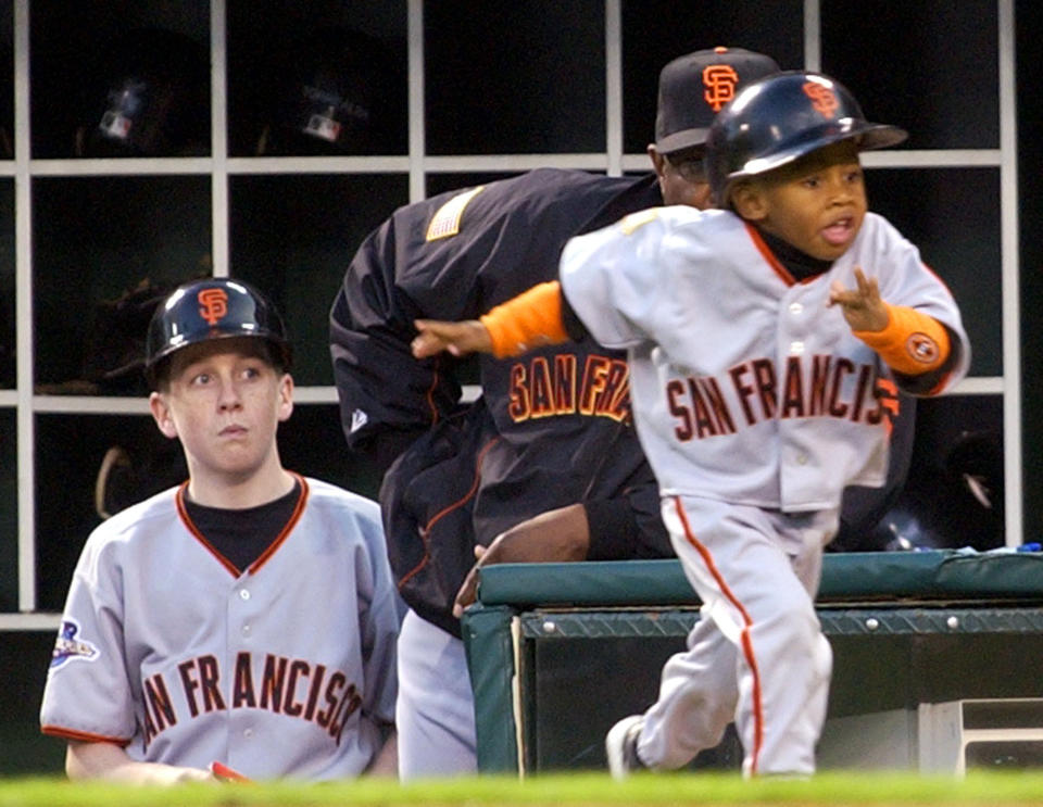 FILE - San Francisco Giants bat boy Darren Baker, right, runs to retrieve a bat during the third inning of game 6 of the World Series Saturday, Oct. 26, 2002 in Anaheim, Calif. At center is Giants manager Dusty Baker and at left is an unidentified bat boy. Darren Baker is now a top prospect and was selected to play in the Futures Game, Saturday, July 16, 2022 at Dodger Stadium. His father Dusty manages the Houston Astros.(AP Photo/Amy Sancetta, File)