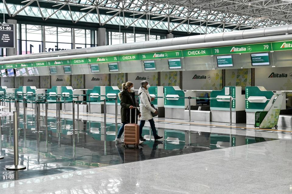 Passengers wearing a respiratory mask walk across the Terminal T1 at Rome's Fiumicino international airport on March 13, 2020. - Rome's Ciampino airport will shut to passenger flights from March 13, authorities said, with a Terminal T1 also closing at the city's main Fiumicino facility next week as airlines slash flights to Italy over the coronavirus outbreak. (Photo by Andreas SOLARO / AFP) (Photo by ANDREAS SOLARO/AFP via Getty Images)