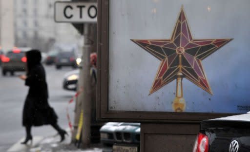 A Russian woman walks past a partly seen election poster in Moscow. Russia has accused the United States of trying to influence its election process by funding opposition groups in advance of Vladimir Putin's expected return to the Kremlin in the weekend poll