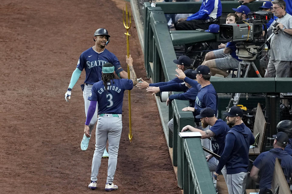 Seattle Mariners' J.P. Crawford (3) gives Julio Rodriguez a trident as they celebrate Rodriguez's two-run home run in the third inning of the team's baseball game against the Texas Rangers in Arlington, Texas, Tuesday, April 23, 2024. (AP Photo/Tony Gutierrez)