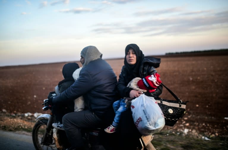 A family leaves on a motorbike as Syrians flee the embattled northern city of Aleppo wait on February 5, 2016