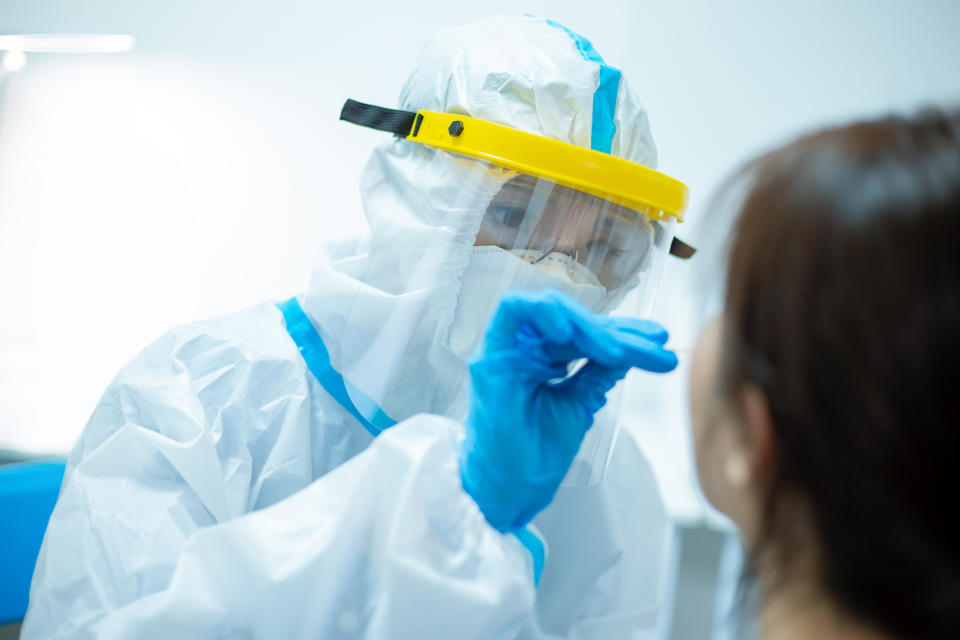 Coronavirus test - Medical worker taking a swab for corona virus sample from potentially infected woman with the isolation gown or protective suits and surgical face masks