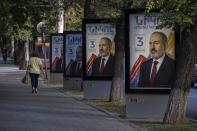 A woman walks past election posters with portraits of Armenian acting Prime Minister Nikol Pashinyan in a street in Yerevan, Armenia. June 16. 2021. Armenians head to the polls Sunday for a snap parliamentary election stemming from a political crisis that has engulfed the former Soviet nation ever since last year's fighting over the separatist region of Nagorno-Karabakh. Acting Prime Minister Nikol Pashinyan called the early vote after facing months of protests demanding his resignation following Armenia's defeat in the Nagorno-Karbakh conflict with Azerbaijan, its neighbor in the Caucasus Mountains region south of Russia. (AP Photo/Areg Balayan)