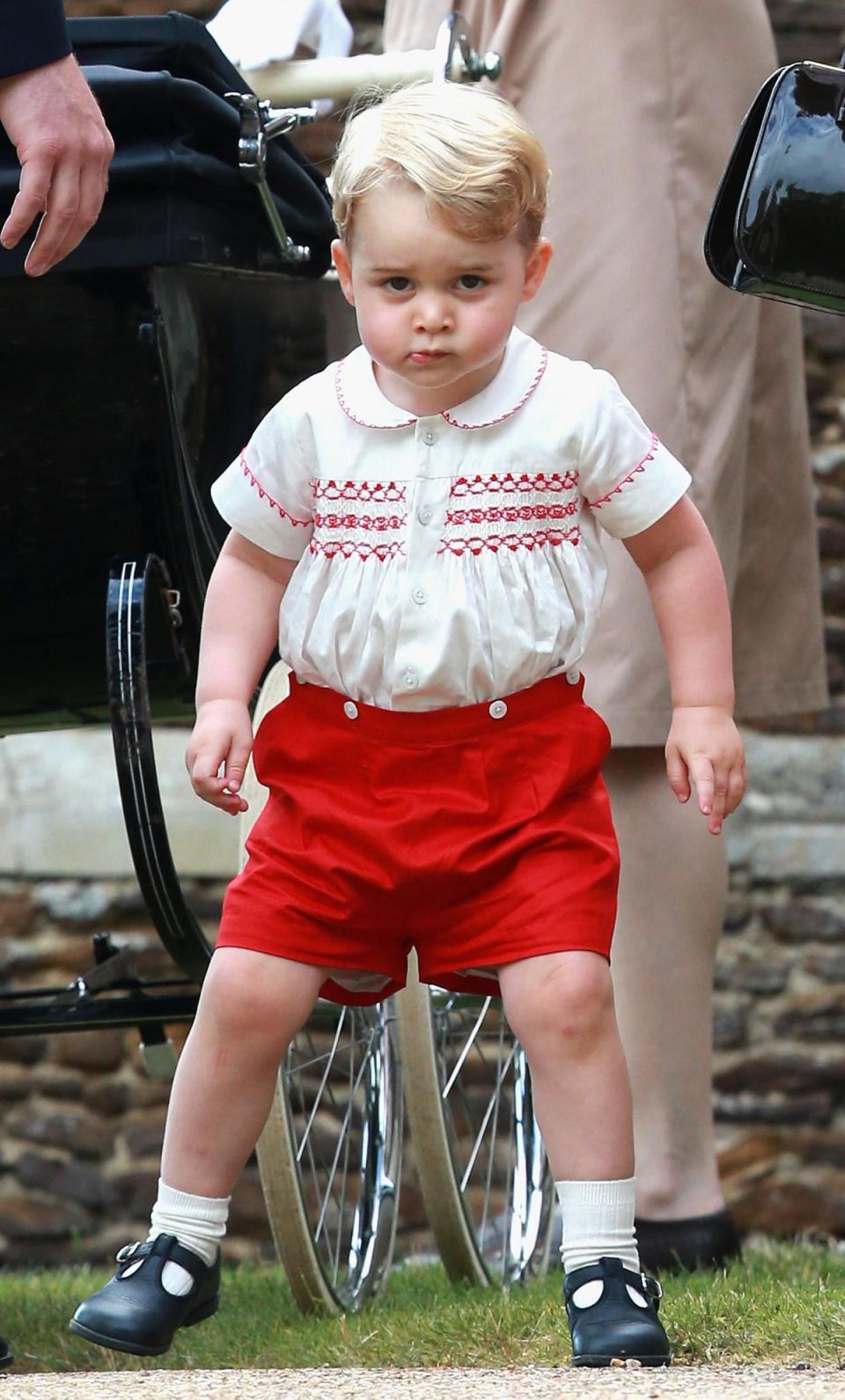 Princess Charlotte, 2015: For his sister, Princess Charlotte’s christening, Prince George wore a pair of smocked red shorts and an embroidered shirt by British designer Rachel Riley.Following his appearance at the church, Riley’s website had sold out of the outside in 12 month and 18 month sizes. The outfit was almost identical to the one worn by his father, the Duke of Cambridge, when he was first taken to see his newborn brother Prince Harry in hospital in 1984. (Getty Images)