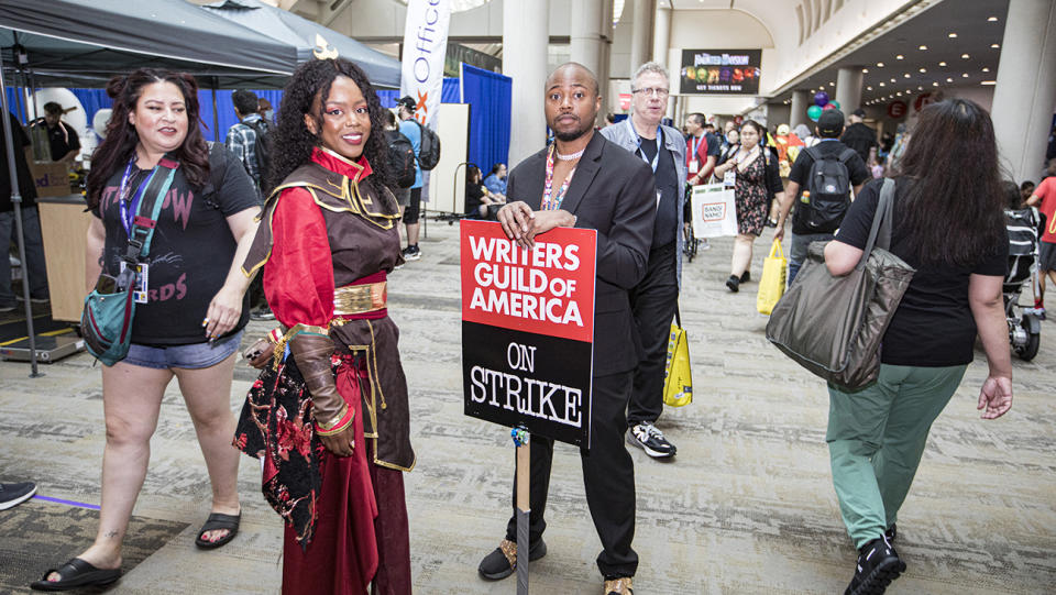 An attendee holds a sign supporting the Writers Guild of America strike at Comic-Con International 2023.