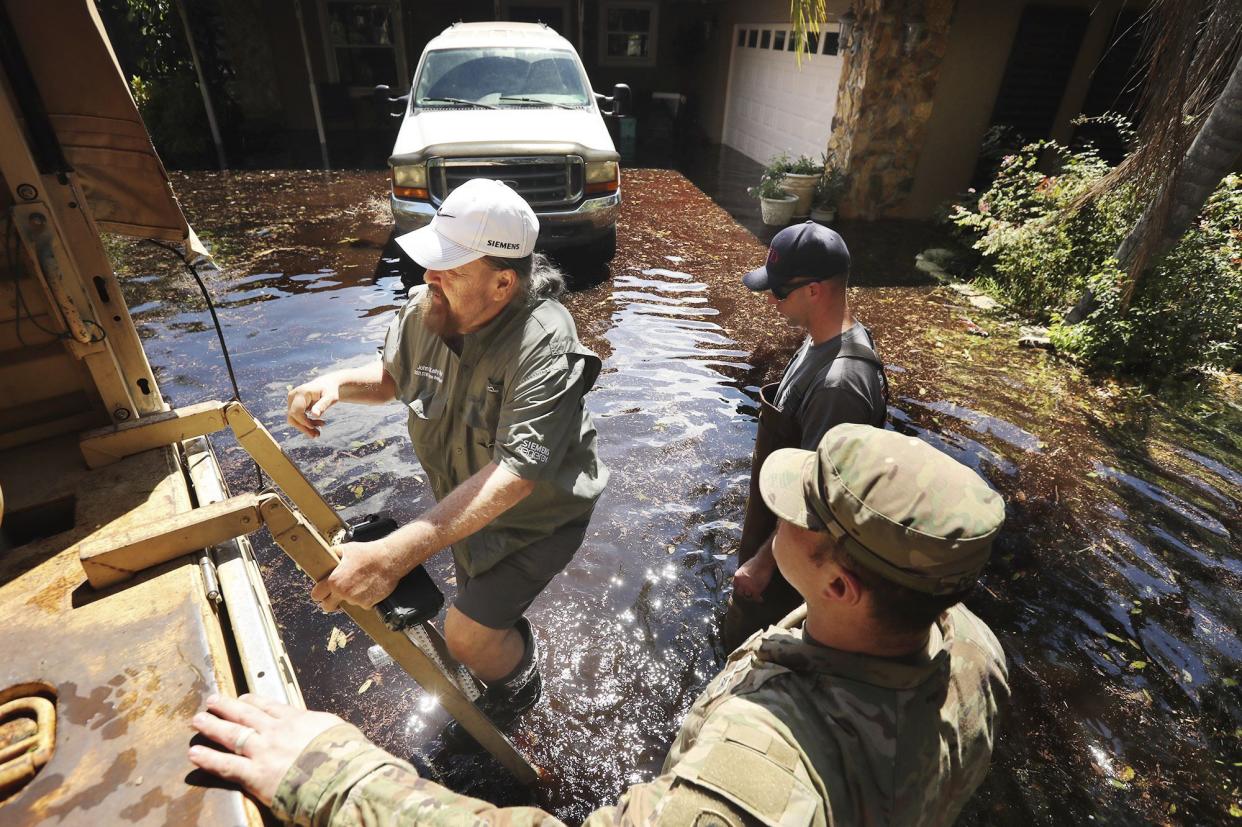 National Guard soldiers rescue a man from his flooded property on Rest Haven Road in Geneva, Fla., Saturday, Oct. 1, 2022. The area is heavily flooded after Hurricane Ian.