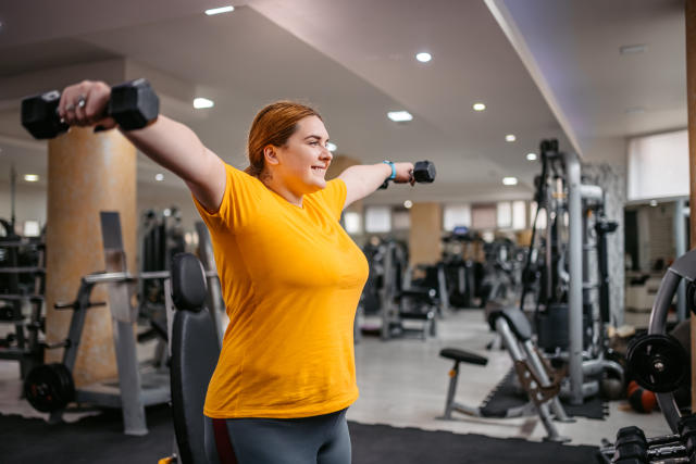 Woman plus size in gym doing exercises with running training