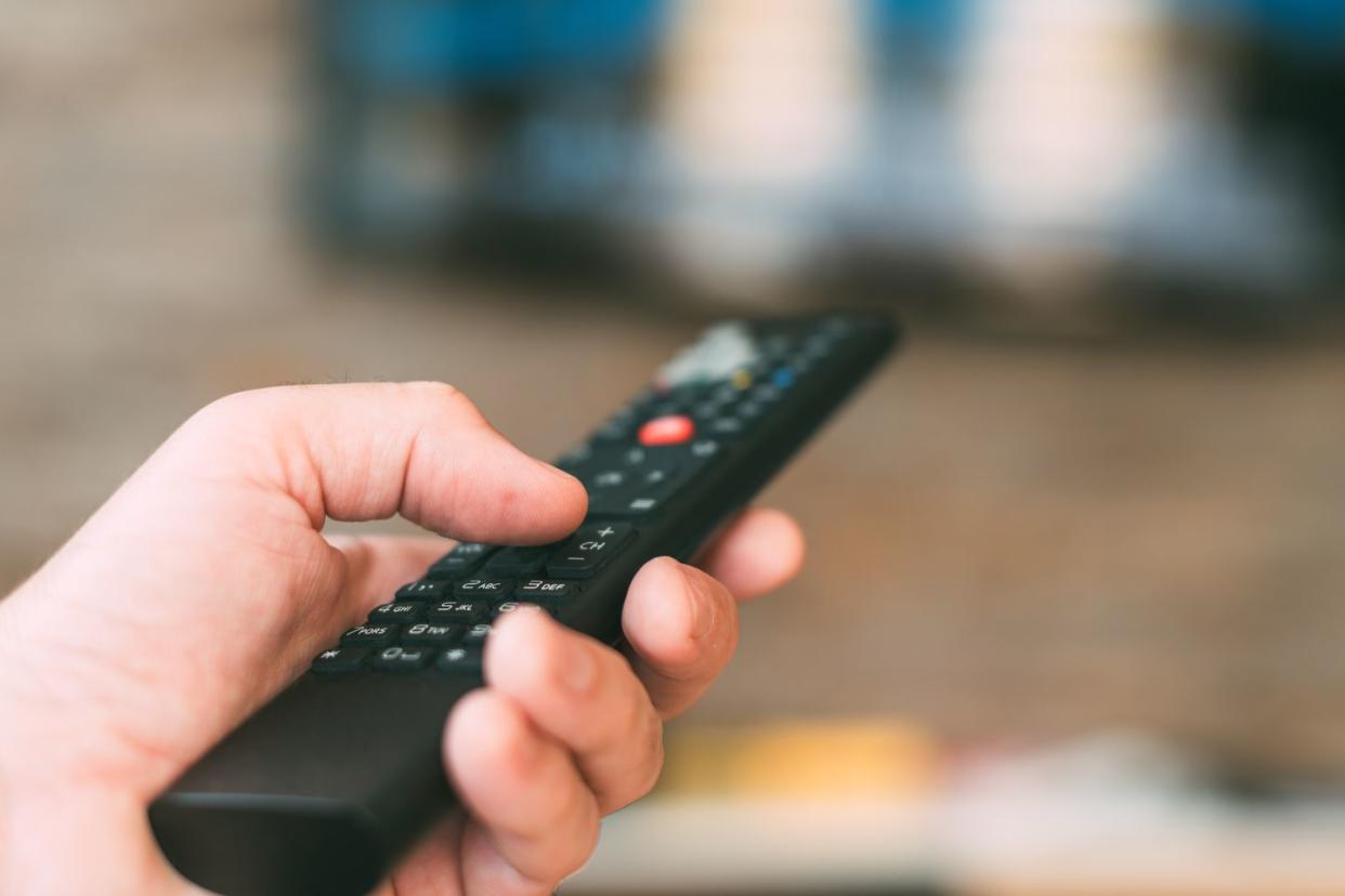 male hand holding television remote controller, close up with selective focus