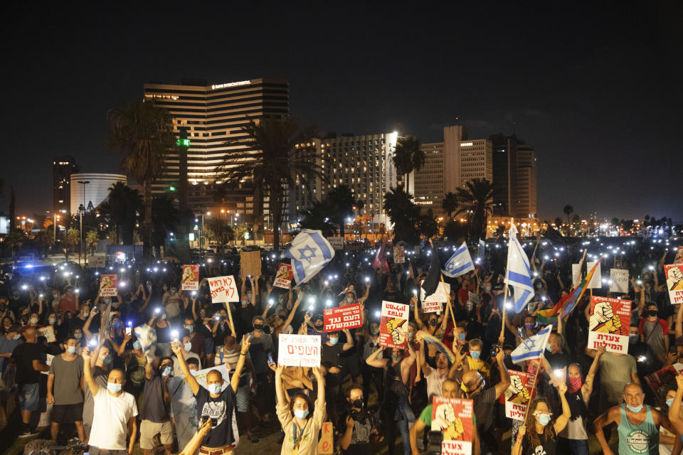 Protesters wearing face masks amid concerns over the country's coronavirus outbreak, hold signs during a protest against Israel's Prime Minister Benjamin Netanyahu in Tel Aviv, Israel, Saturday, July 25, 2020. Protesters demanded that the embattled Israeli leader resign as he faces a trial on corruption charges and grapples with a deepening coronavirus crisis. (AP Photo/Oded Balilty)