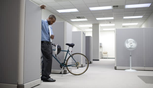 Businessman in cubicle with bicycle