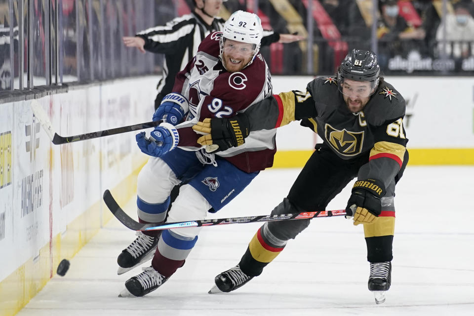 Vegas Golden Knights right wing Mark Stone (61) and Colorado Avalanche left wing Gabriel Landeskog (92) battle for the puck during the third period of an NHL hockey game Monday, May 10, 2021, in Las Vegas. (AP Photo/John Locher)