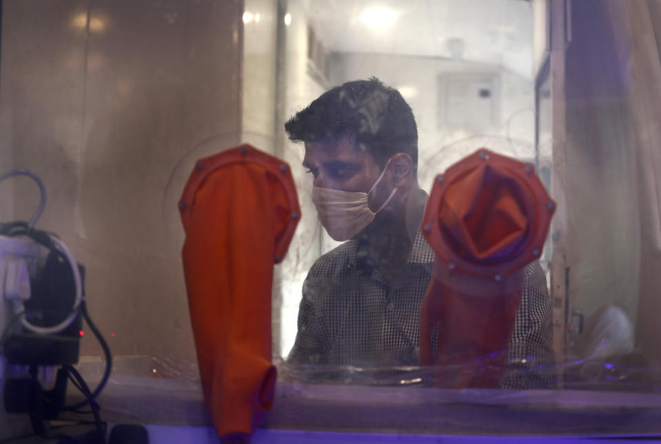 FILE - In this Aug. 10, 2020, file photo, a person waits to give nasal swab sample for a COVID- 19 antigen test inside a mobile lab in New Delhi, India. In June, India began using the cheaper, faster but less accurate tests to scale up testing for the coronavirus — a strategy that the U.S. is now considering. (AP Photo/Manish Swarup, File)