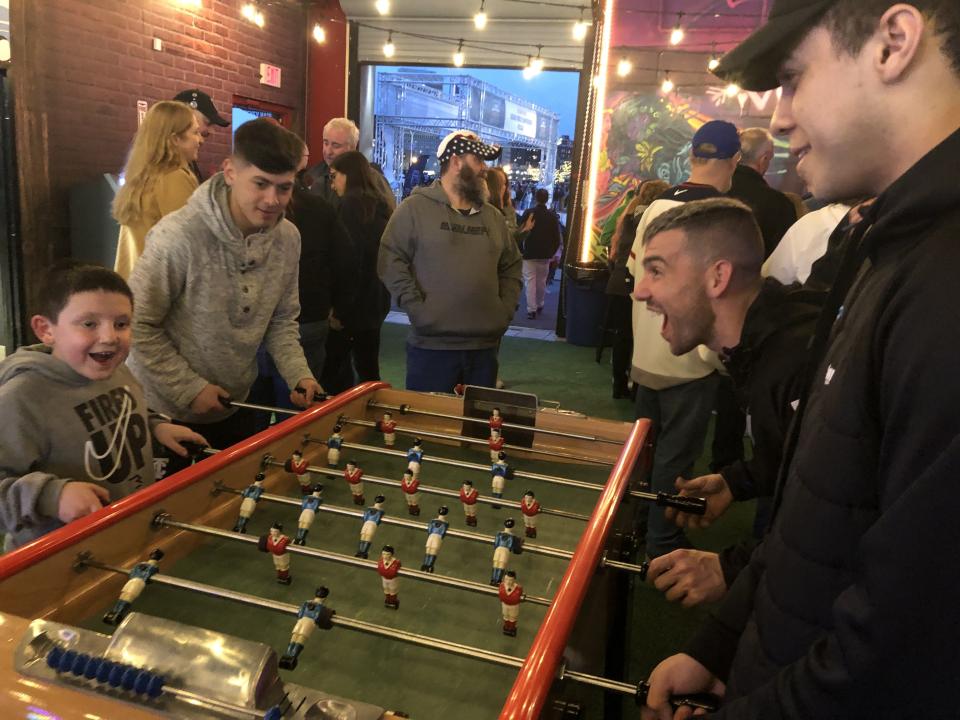 Julian Rodriguez, right, Gordy Gurson, next to Rodriguez, Ricardo Rozco, center, all players for the Utica City Football Club, and Gurson's son Enid, 8, play foosball on April 11, 2024 at the Subaru World Championship Village set up by the Adirondack Bank Center at the Utica Memorial Auditorium for the International Ice Hockey Federation Women's World Championship tournament in Utica.
