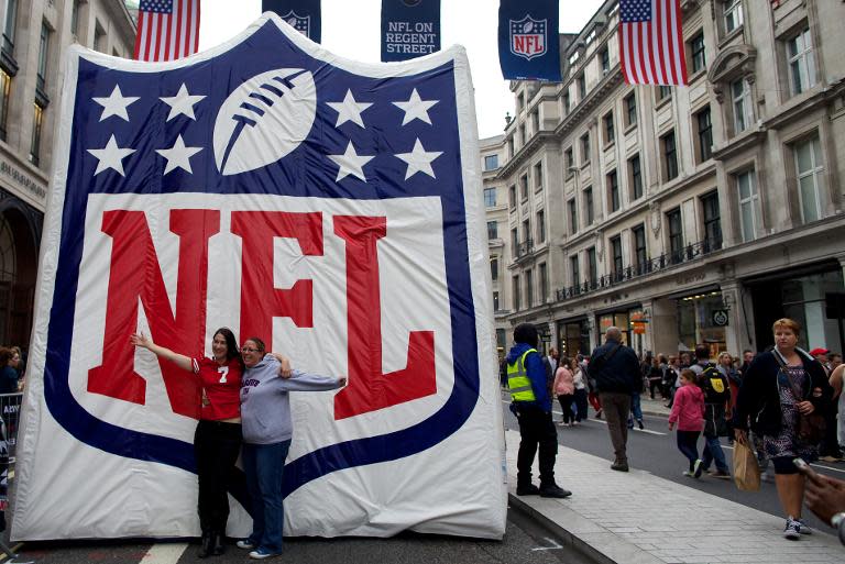 People pose for a picture in front of a giant NFL sign on September 28, 2013 in London, where NFL International Executive Vice President Mark Waller said the league is on track for a potential team by 2022