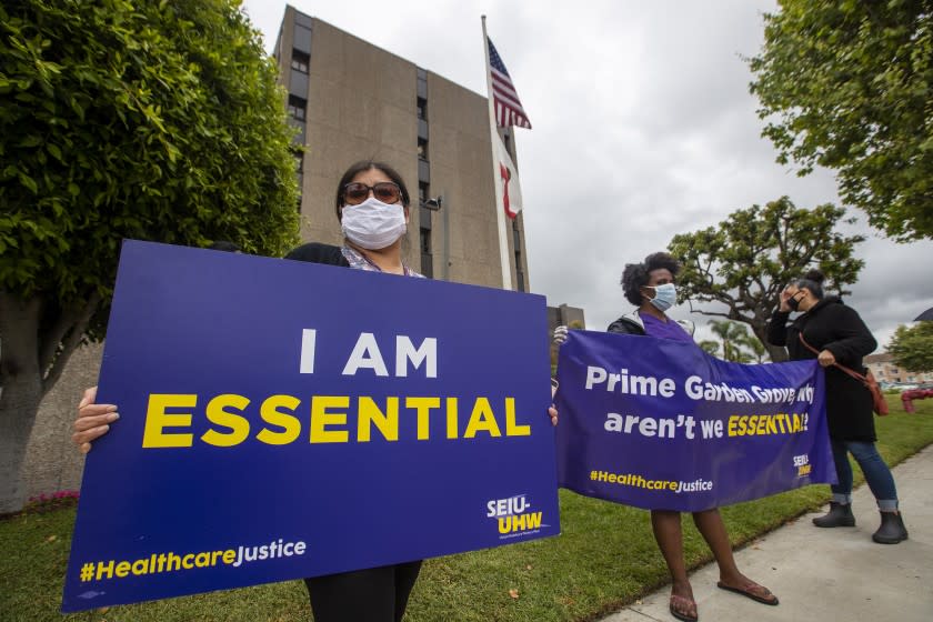 GARDEN GROVE, CA - MAY 18: Rosanelli Phan, left, Garden Grove Hospital medical records dept. worker, protests with fellow SEIU-UHW United Healthcare Workers West union members at Garden Grove Hospital Medical Center on Monday, May 18, 2020 in Garden Grove, CA. Workers at hospitals owned by Prime Healthcare said they picketed the facilities over the corporation's attempt to cut their sick time and disability even as the employees risk their health treating Covid-19 patients. (Allen J. Schaben / Los Angeles Times)