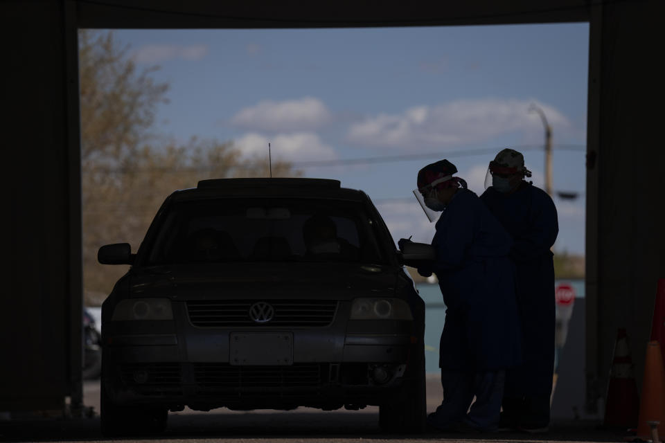 FILE - In this on April 20, 2020, file photo, Dr. Diana Hu, left, and a colleague wear personal protective equipment (PPE) as they work in the COVID-19 screening and testing tent in the parking lot at Tuba City Regional Health Care on the Navajo Reservation in Tuba City, Ariz. Indian tribes across the country are wrestling with competing needs, restrictive laws and inadequate staffing as they try to meet a tight federal deadline on spending billions of dollars in virus relief funds. (AP Photo/Carolyn Kaster, File)