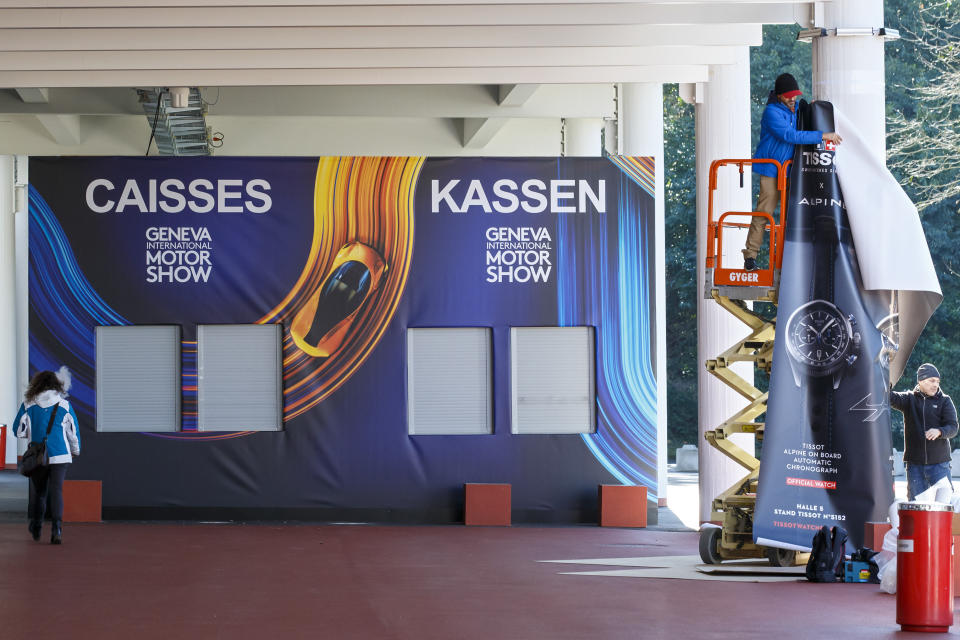 Workers stop the preparation of the 90th Geneva International Motor Show, GIMS, at Palexpo, in Geneva, Switzerland, Friday, Feb. 28, 2020. The 90th edition of the International Motor Show, scheduled to begin on March 5th, is cancelled due to the advancement of the (Covid-19) coronavirus in Switzerland. The Swiss confederation announced today that all events involving more than 1,000 people would be banned until 15 March. (Salvatore di Nolfi/Keystone via AP)