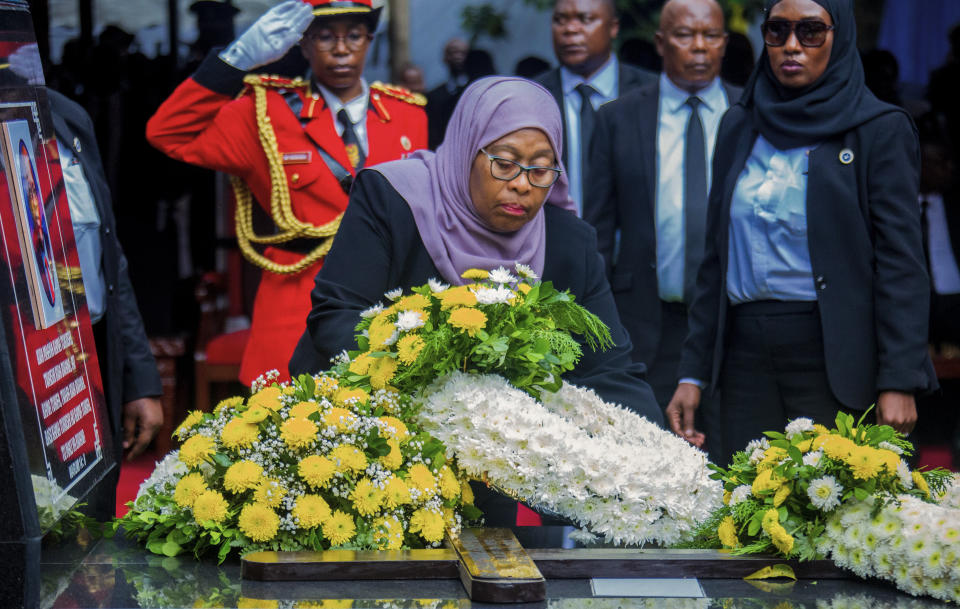 President Samia Suluhu Hassan places flowers on the grave of former President John Magufuli in his home town of Chato, Tanzania Friday, March 26, 2021. Thousands have gathered in the northwestern town of Chato for the burial of former Tanzanian President John Magufuli whose denial of COVID-19 brought the country international criticism. (AP Photo)