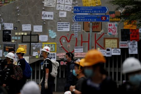 People walk next to notes and placards showing support for the protest against the extradition bill, along a road near the Legislative Council building, in Hong Kong