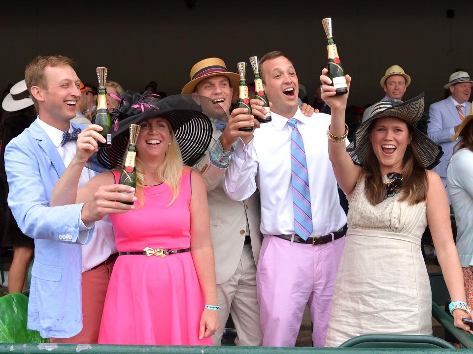 people cheering and holding champagne at the kentucky derby