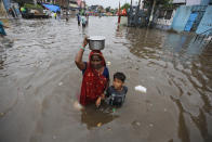 An Indian woman and a child wade past floodwaters after heavy rainfall in Ahmadabad, India, Friday, Aug. 17, 2018. India receives its annual rainfall from June-October. (AP Photo/Ajit Solanki)