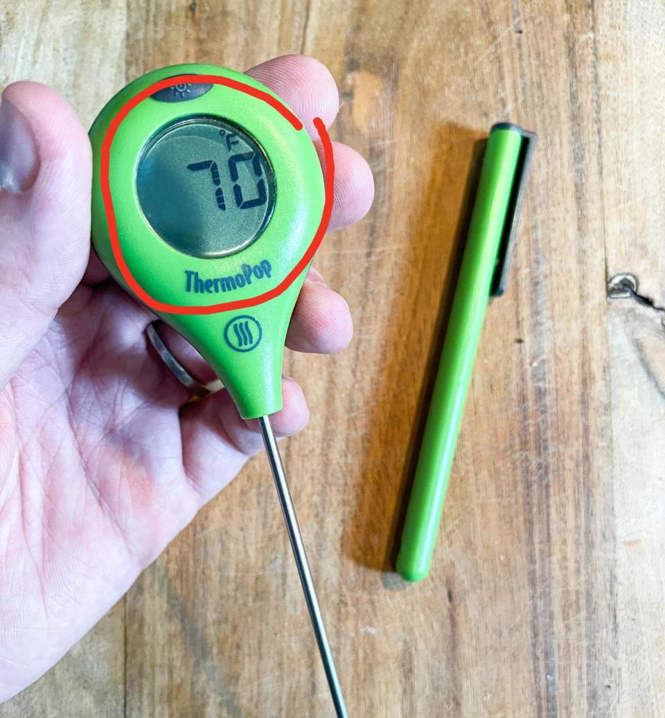 Author holding a green ThermoPop thermometer registering at 70º