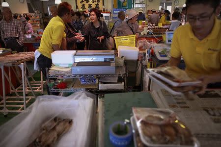 People buy fish at a market in the Iwaki town, south of the tsunami-crippled Daiichi nuclear power plant in Fukushima prefecture in this September 19, 2013 file photo. REUTERS/Damir Sagolj