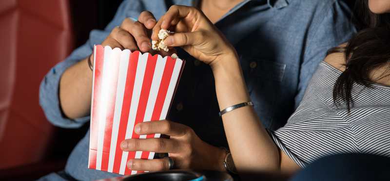 Two moviegoers share popcorn.