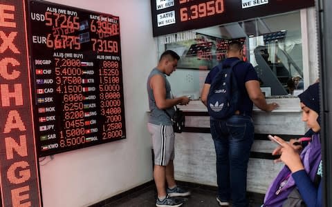 People check currency exchange rates at a currency exchange office in Istanbul - Credit: AFP