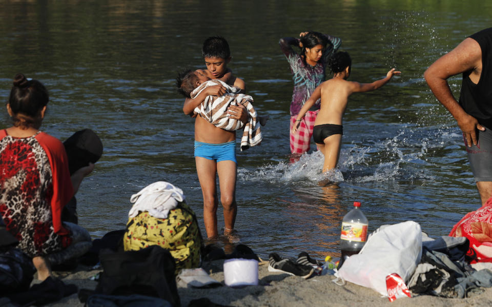 Una familia de migrantes hondureños se baña en el río Suchiate, cerca de Tecún Umán, Guatemala, el miércoles 22 de enero de 2020. (AP Foto/Marco Ugarte)