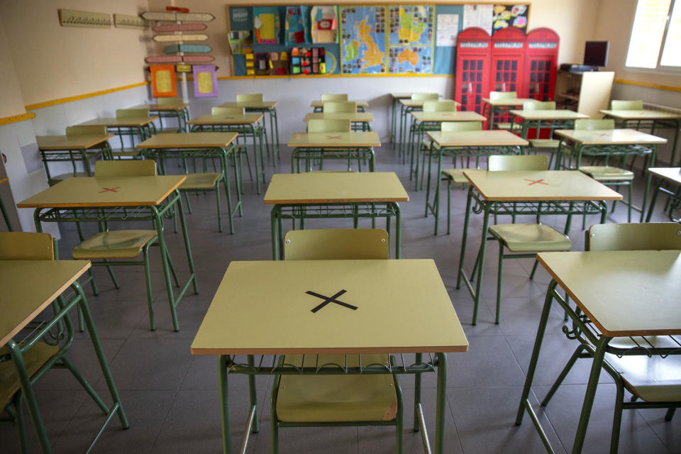 Pupitres que no se utilizarán aparecen marcados para mantener la distancia social en una escuela secundaria en Sevilla la Nueva, en Madrid, España, el lunes 31 de agosto de 2020. (AP Foto/Andrea Comas)