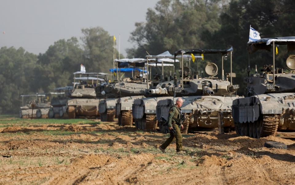 An Israeli soldier walks next to a convoy of tanks