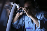 Vietnamese Air Force Col. Pham Minh Tuan uses binoculars on board a flying aircraft during a mission to search for the missing Malaysia Airlines flight MH370 in the Gulf of Thailand, Thursday, March 13, 2014. With no distress call, no sign of wreckage and very few answers, the disappearance of the Malaysia Airlines plane is turning into one of the biggest aviation mysteries since Amelia Earhart vanished over the Pacific Ocean in 1937. (AP Photo)