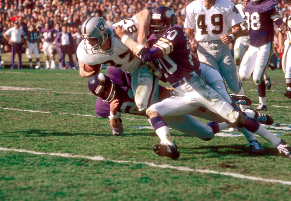 Oakland Raiders tight end Dave Casper (87) is brought down by Minnesota Vikings defensive back Bobby Bryant (20) during Super Bowl XI at the Rose Bowl in 1977. The Raiders defeated the Vikings 32-14 to win their first Super Bowl Championship. Casper, a Notre Dame grad, scored a touchdown.