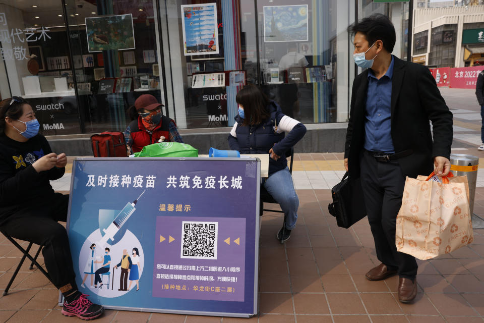 A shopper walks past a stand offering free tickets to tourist sites as part of its campaign to encourage coronavirus vaccinations with the slogan, "Timely vaccination to build the Great Wall of Immunity together" in Beijing on Friday, April 9, 2021. China's success at controlling the coronavirus outbreak has resulted in a population that has seemed almost reluctant to get vaccinated. Now, it is offering incentives — free eggs, store coupons and discounts on groceries and merchandise — to those who get a shot. (AP Photo/Ng Han Guan)