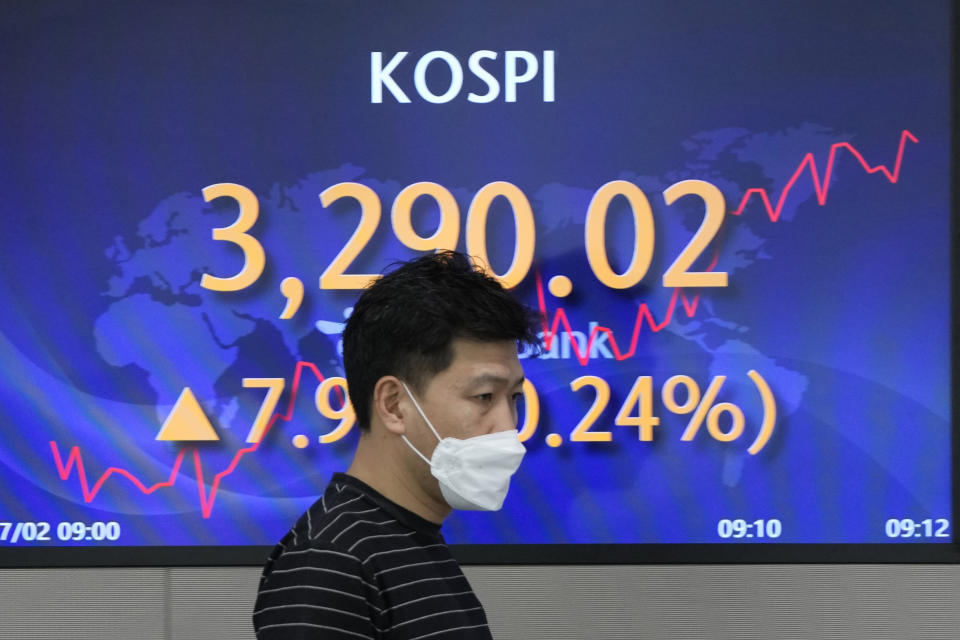 A currency trader walks near a screen showing the Korea Composite Stock Price Index (KOSPI) at a foreign exchange dealing room in Seoul, South Korea, Friday, July 2, 2021. Shares were mostly higher in Asia on Friday, though markets in Shanghai and Hong Kong declined a day after the Chinese Communist Party marked its centenary with tough talk by Chinese President Xi Jinping. (AP Photo/Lee Jin-man)