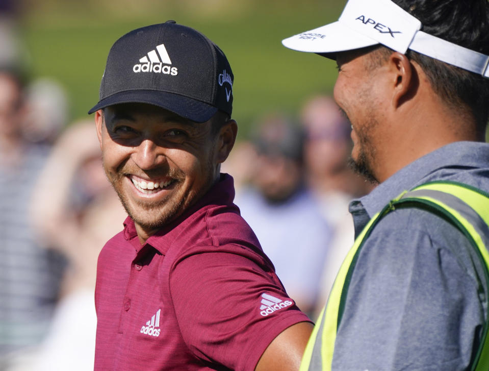 Xander Schauffele laughs with his caddie on the ninth hole during the second round of the Phoenix Open golf tournament Friday, Feb. 11, 2022, in Scottsdale, Ariz. (AP Photo/Darryl Webb)