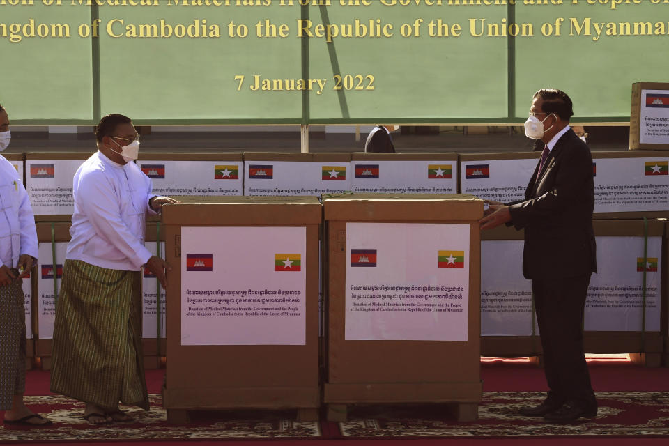 In this photo provided by An Khoun Sam Aun/National Television of Cambodia, Cambodian Prime Minister Hun Sen, right, hands over the medical materials to Myanmar Foreign Minister Wunna Maung Lwin, left, in Naypyitaw, Myanmar, Friday, Jan 7, 2022. (An Khoun SamAun/National Television of Cambodia via AP)