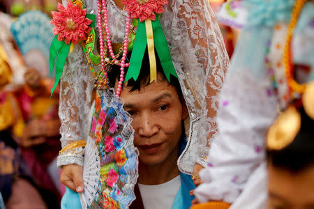 A man carries a boy on shoulders during an annual Poy Sang Long procession, a traditional rite of passage for boys to be initiated as Buddhist novices, in Mae Hong Son, Thailand, April 3, 2018. REUTERS/Jorge Silva