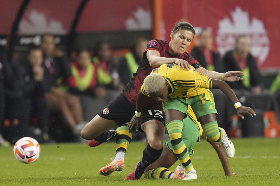 Canada's Christine Sinclair (12) and Jamaica's Deneisha Blackwood (14) battle for the ball during the second half of a CONCACAF women's championship soccer series match in Toronto on Tuesday Sept. 26, 2023. (Nathan Denette/The Canadian Press via AP)