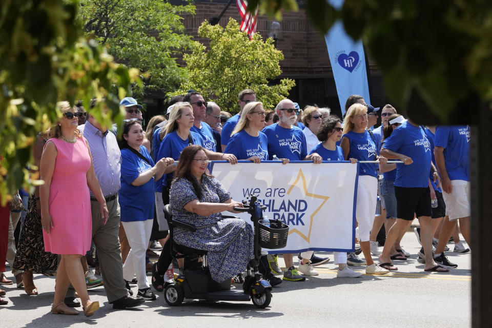 Sen. Tammy Duckworth, center, D-Ill., and people participate in a community walk in Highland Park, Ill., Tuesday, July 4, 2023 .One year after a shooter took seven lives at the city's annual parade, community members are planning to honor the victims and reclaim the space to move forward. (AP Photo/Nam Y. Huh)