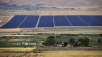 A solar farm sits behind homes Tuesday, Aug. 9, 2022, in Mona, Utah. The U.S. has renewed credibility on global climate issues and will be able to inspire other nations in their own efforts, experts say, after the Democrats pushed their big economic bill through the Senate on Sunday, Aug. 7. (AP Photo/Rick Bowmer)