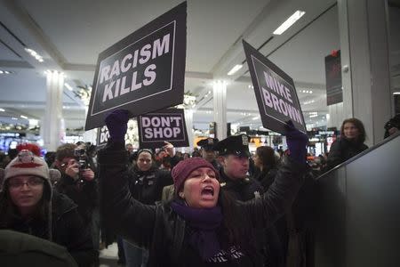 A protester marches though Macy's store chanting "Hands up, don't shop" in support of the late Michael Brown in New York November 28, 2014. REUTERS/Carlo Allegri