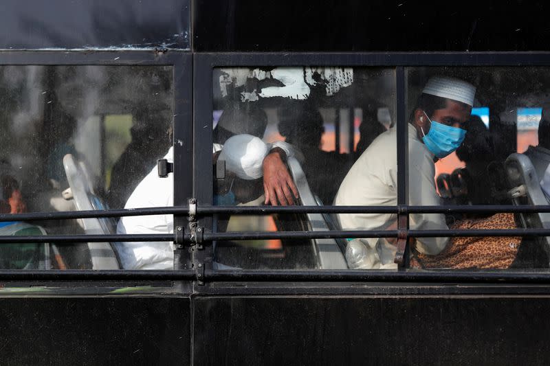 Men wearing protective masks sit inside a bus that will take them to a quarantine facility, amid concerns about the spread of coronavirus disease (COVID-19), in Nizamuddin area of New Delhi