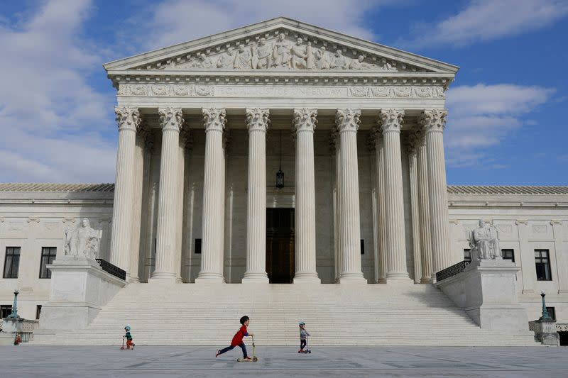 FILE PHOTO: Children ride scooters across the plaza at the United States Supreme Court, following the government's notice to halt all building tours due to the (COVID-19) coronavirus, on Capitol Hill in Washington
