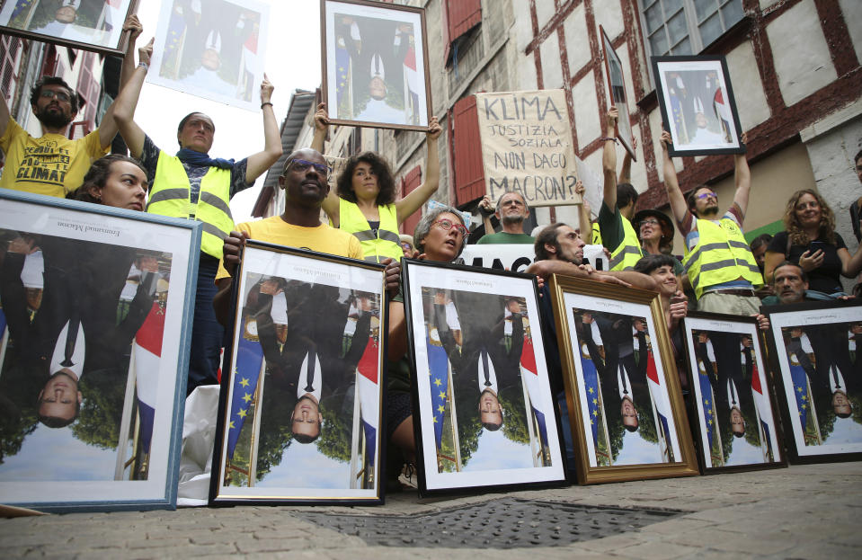 Demonstrator hold upside down portraits of French President Emmanuel Macron during a protest through the streets of Bayonne, France Sunday, Aug. 25, 2019. Critics of French President Emmanuel Macron are marching near the G-7 summit he is hosting to demand he do more to protect French workers and the planet. A melange of activists, some wearing yellow vests, carried portraits of Macron as they marched Sunday through the southwest city of Bayonne. Some held the portraits upside down. (AP Photo/Bob Edme)